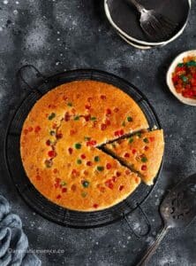 Overhead shot of eggless sooji cake on a round wire rack against a dark backdrop