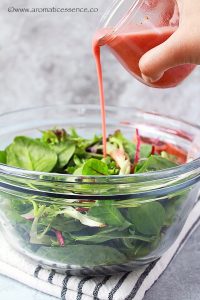 Drizzling blood orange dressing over greens