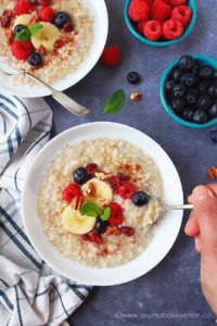 Steel Cut Oats in a white bowl topped with berries, banana slices, and chopped pecans