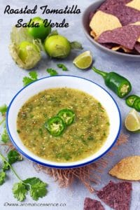 Salsa verde in a white bowl, garnished with serrano pepper slices.