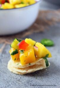 Mango salsa on top of a stack of tortilla chips.