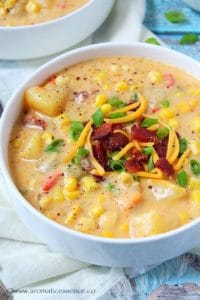 Corn chowder served in a white soup bowl.