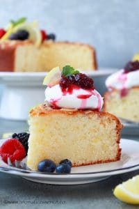 Close-up shot of ricotta cake topped with whipped cream and berry compote