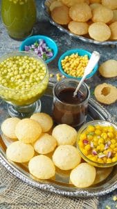 Puris, spicy pani, ragda, and sweet chutney on a platter