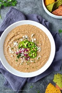 Instant Pot refried beans served in a white shallow speckled bowl.
