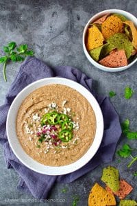 Refried beans in a white shallow bowl.