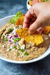Scooping refried beans with a tortilla chip