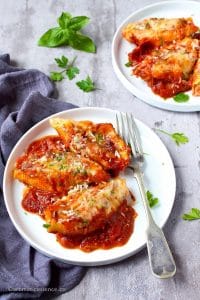 Stuffed jumbo shells served in 2 white rimmed plates.