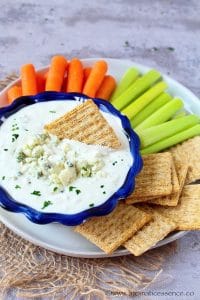 Blue cheese dipping sauce served with crackers, celery sticks, and carrots.