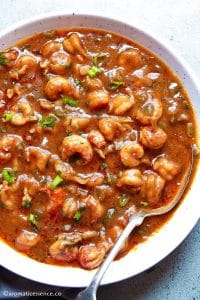 Cajun crawfish etouffee served in a white speckled shallow bowl