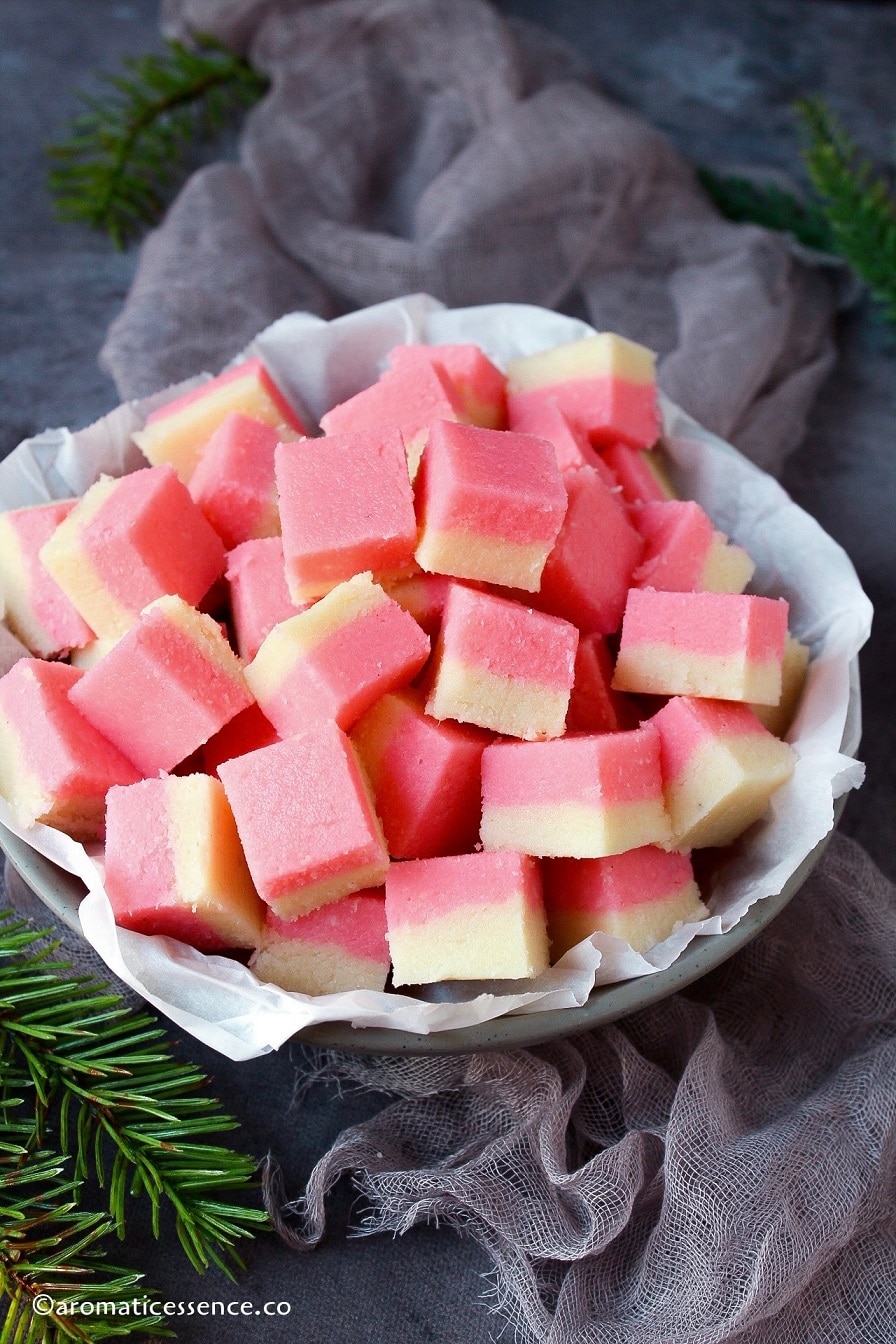 Coconut ice squares placed in a grey shallow bowl 