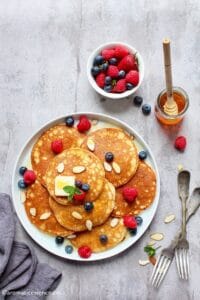 Almond pancakes topped with syrup, butter, and fresh berries