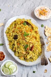 Mint rice served with boondi raita, cucumber slices, and papad