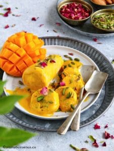 45 degree angle shot of two mango kesar kulfi's on a marble plate, one whole and one sliced into discs