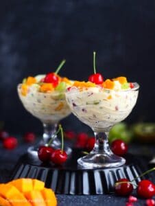 Fruit cream topped with cherries, mangoes, grapes, and pomegranate arils
