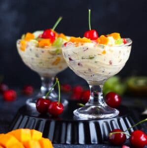 fruit cream topped with cherries, mangoes, grapes, and pomegranate arils