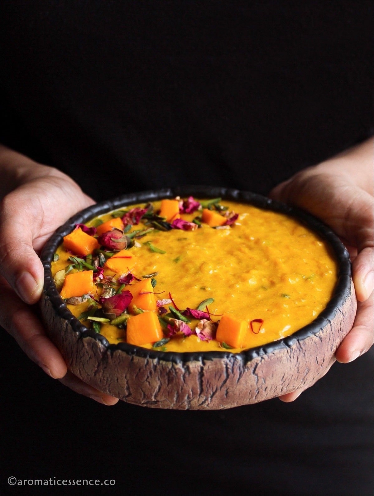 Hands holding a bowl of mango kheer
