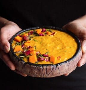 Hands holding a bowl of mango kheer