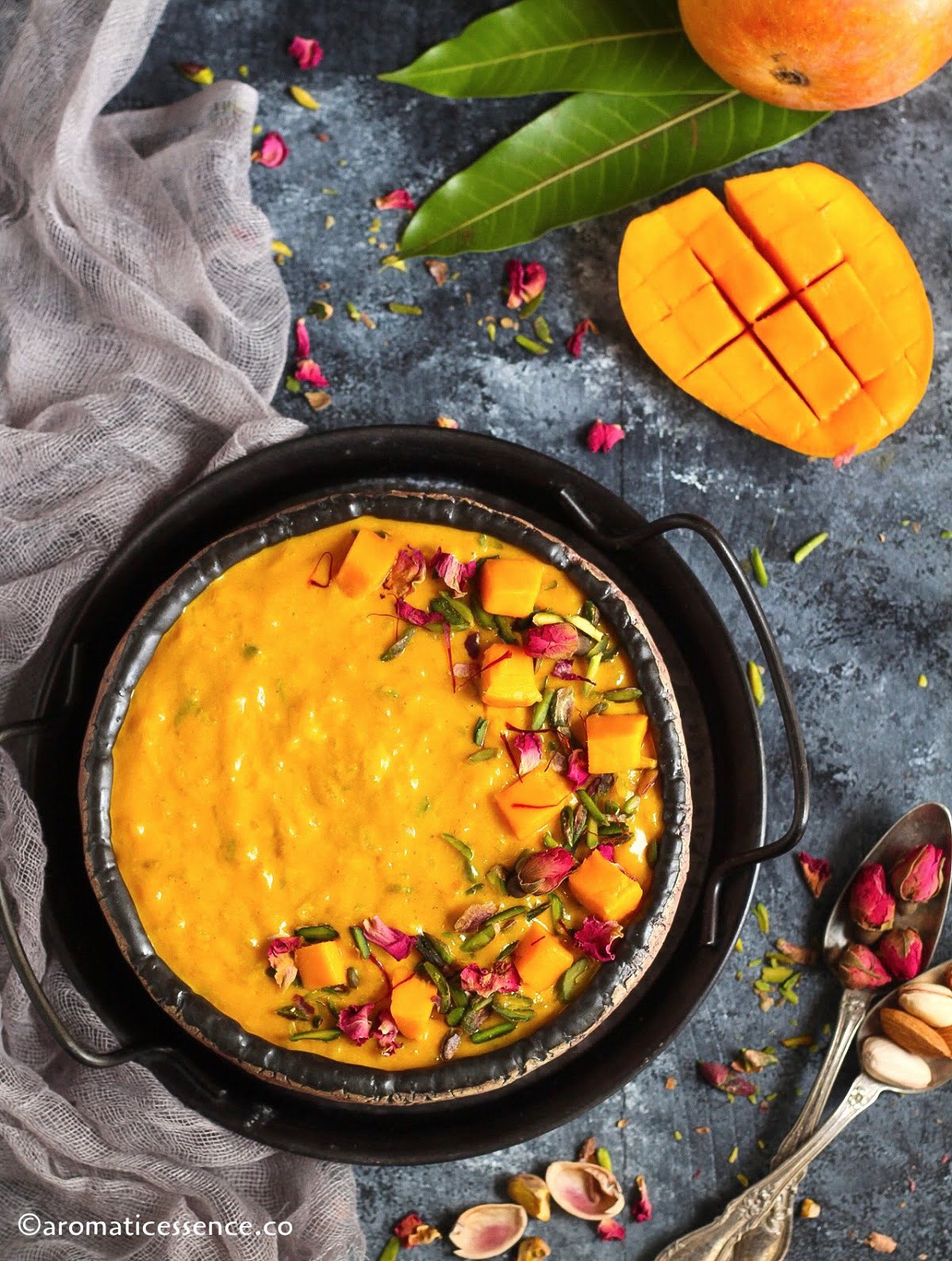 Overhead shot of Indian mango rice pudding with mangoes and mango leaves in the background