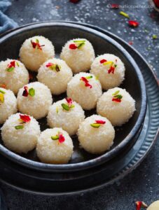 Desiccated coconut ladoos in a black stoneware bowl