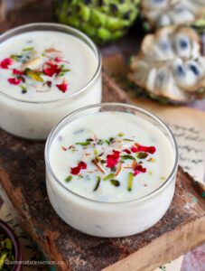 Close-up shot of custard apple basundi garnished with dried rose petals and nuts in two serving bowls