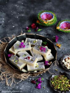 Mawa barfi pieces served in a black metal plate