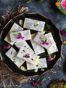 Close-up, overhead shot of khoye ki burfi garnished with edible flowers.