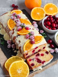 Cranberry orange loaf garnished with orange wedges, sugared cranberries, and rosemary sprigs