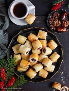 Overhead shot of date rolls in a black fluted metal tray served with a cup of black coffee