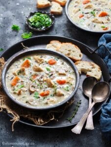 45 degree angle shot of Instant Pot chicken wild rice mushroom soup served in a black bowl along with crusty bread