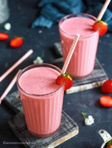 45 degree angle shot of strawberry lassi in 2 glasses garnished with strawberry halves