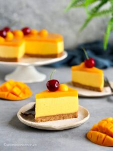 Two slices of no-bake mango cheesecake served on two irregular off-white dessert plates