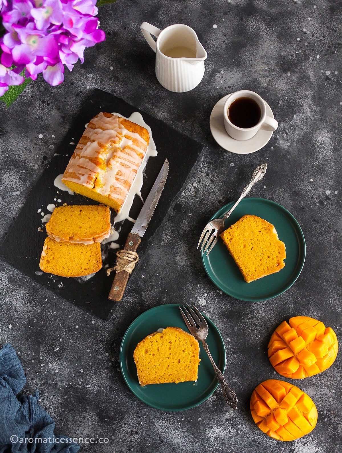 Two slices of eggless mango loaf cake served on dark green dessert plates