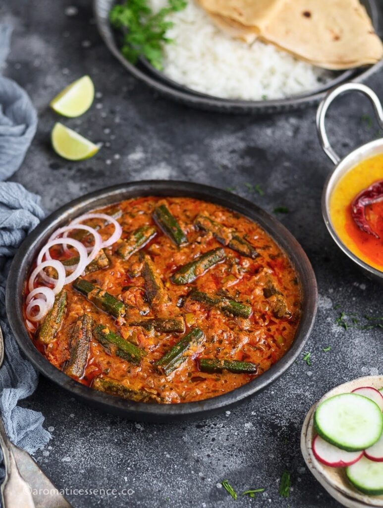 Bhindi masala gravy served in a black earthen shallow bowl