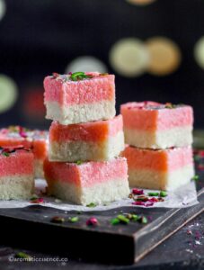 Stack of rose coconut barfi against a bokeh background