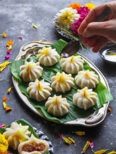 Drizzling ghee over modak