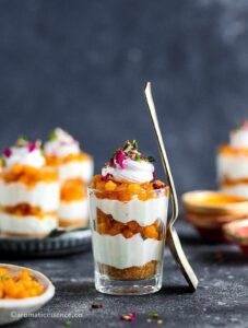 A glass of boondi cheesecake shots in focus against more cheesecake shots in the background